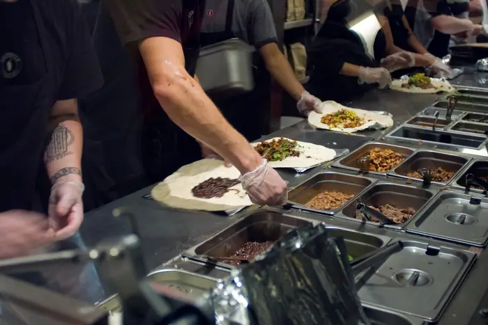 Workers prepare burritos at a Chipotle Mexican Grill in Midtown in New York.